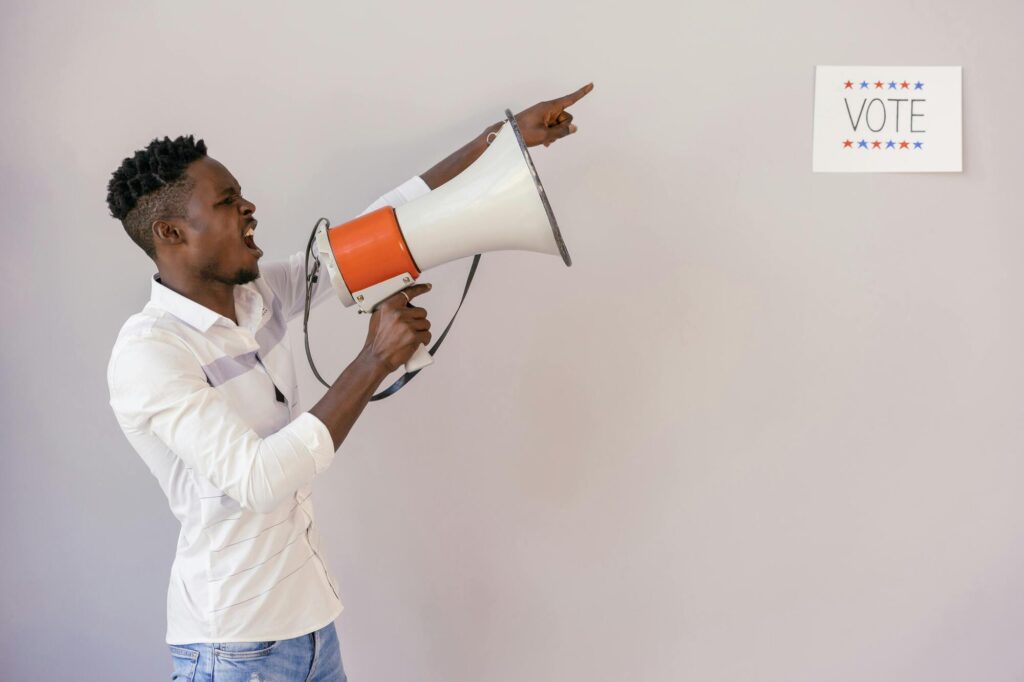 Man with megaphone pointing offstage left.